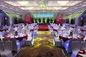 A banquet hall with round tables, white chairs, and a stage at the front. - Tomorrow Wuzhou Hotel (Beijing West Railway Station Lize Business District) (Beijing)