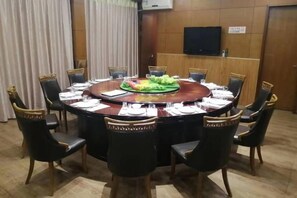 Una sala de conferencias con una mesa redonda, sillas y una televisión en la pared.