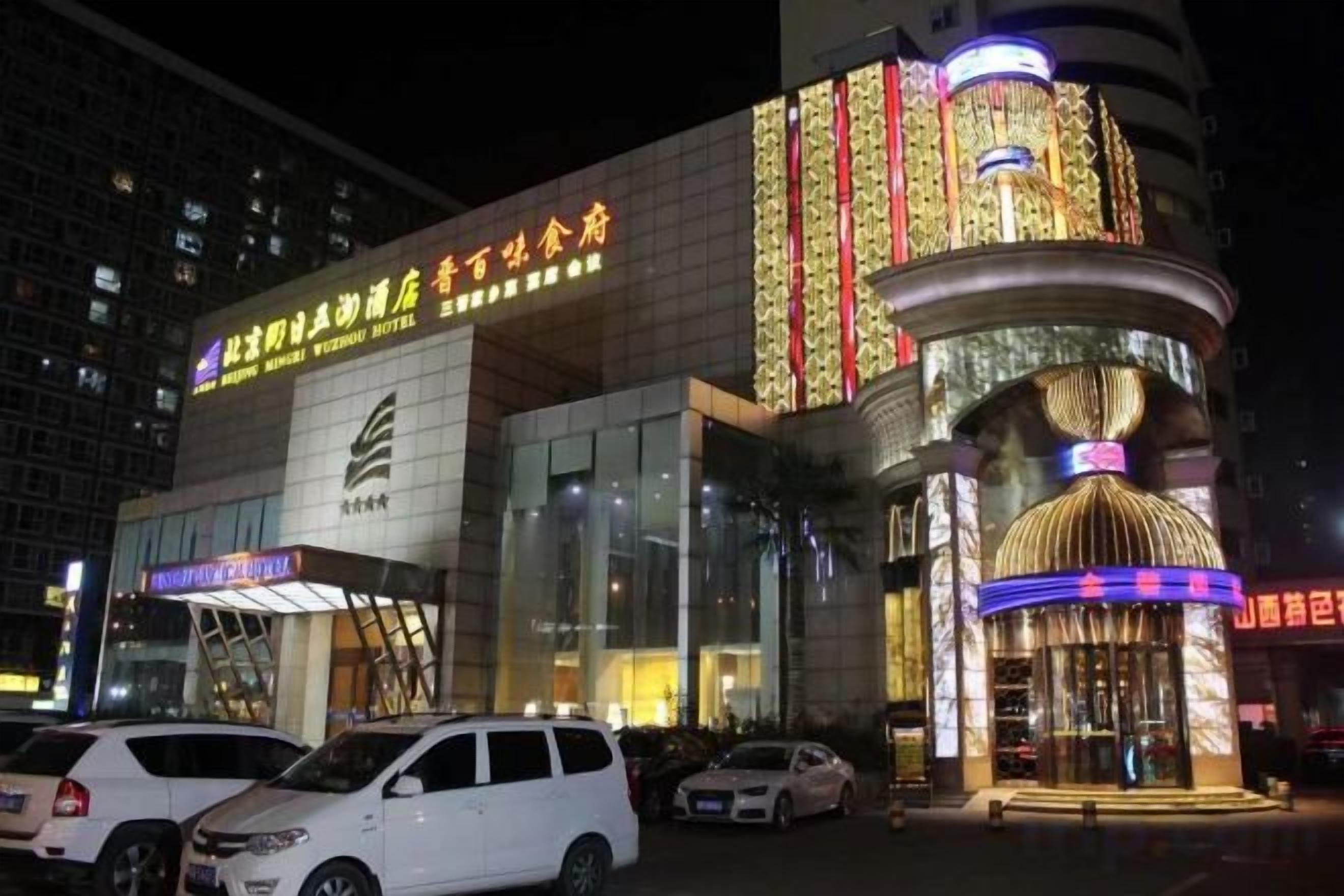 A hotel with a prominent entrance, multiple parking spaces, and a large, illuminated marquee.