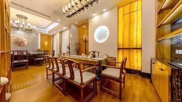 A spacious dining area with a wooden table and chairs, a chandelier, and a large window with a view.