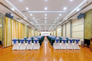 A conference room with rows of tables and chairs, a wooden floor, and a patterned wall on one side. - Tomorrow Wuzhou Hotel (Beijing West Railway Station Lize Business District) (Beijing)