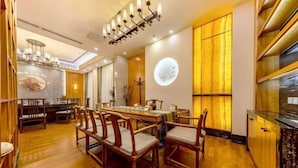 A dining area with a wooden table and chairs, a chandelier, and a wall clock. - Tomorrow Wuzhou Hotel (Beijing West Railway Station Lize Business District) (Beijing)