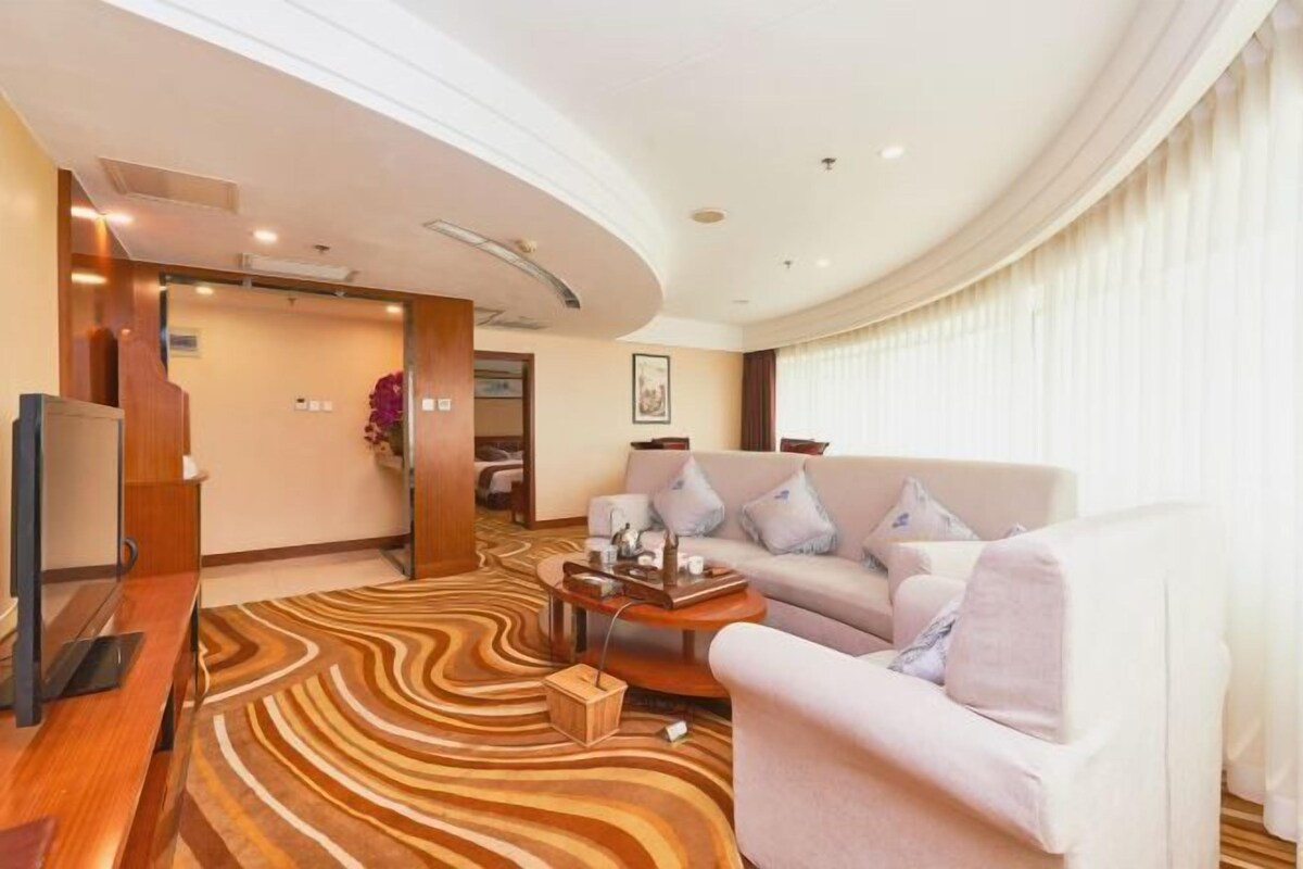 A modern hotel room with a curved ceiling, a sofa, a coffee table, and a TV.