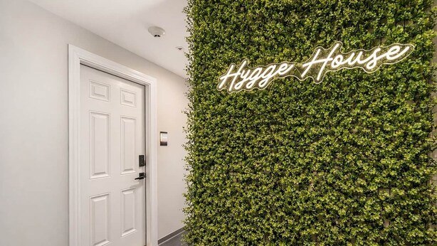 A hallway with a white door and a wall covered in green foliage. - Jade Suite at The Hygge House (Newburyport)