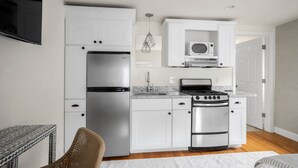 A modern kitchen with white cabinets, stainless steel appliances, a microwave, and a built-in oven. - Jade Suite at The Hygge House (Newburyport)