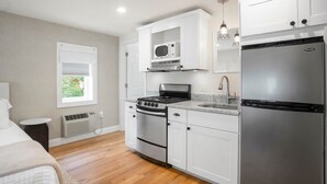 Una cocina moderna con armarios blancos, un refrigerador de acero inoxidable, un horno empotrado y un microondas.