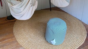 A room with two macramé hammocks, a round woven rug, and a blue patterned ottoman. - Lake Cottage - Put your Feet up and Relax! (Moultonborough)