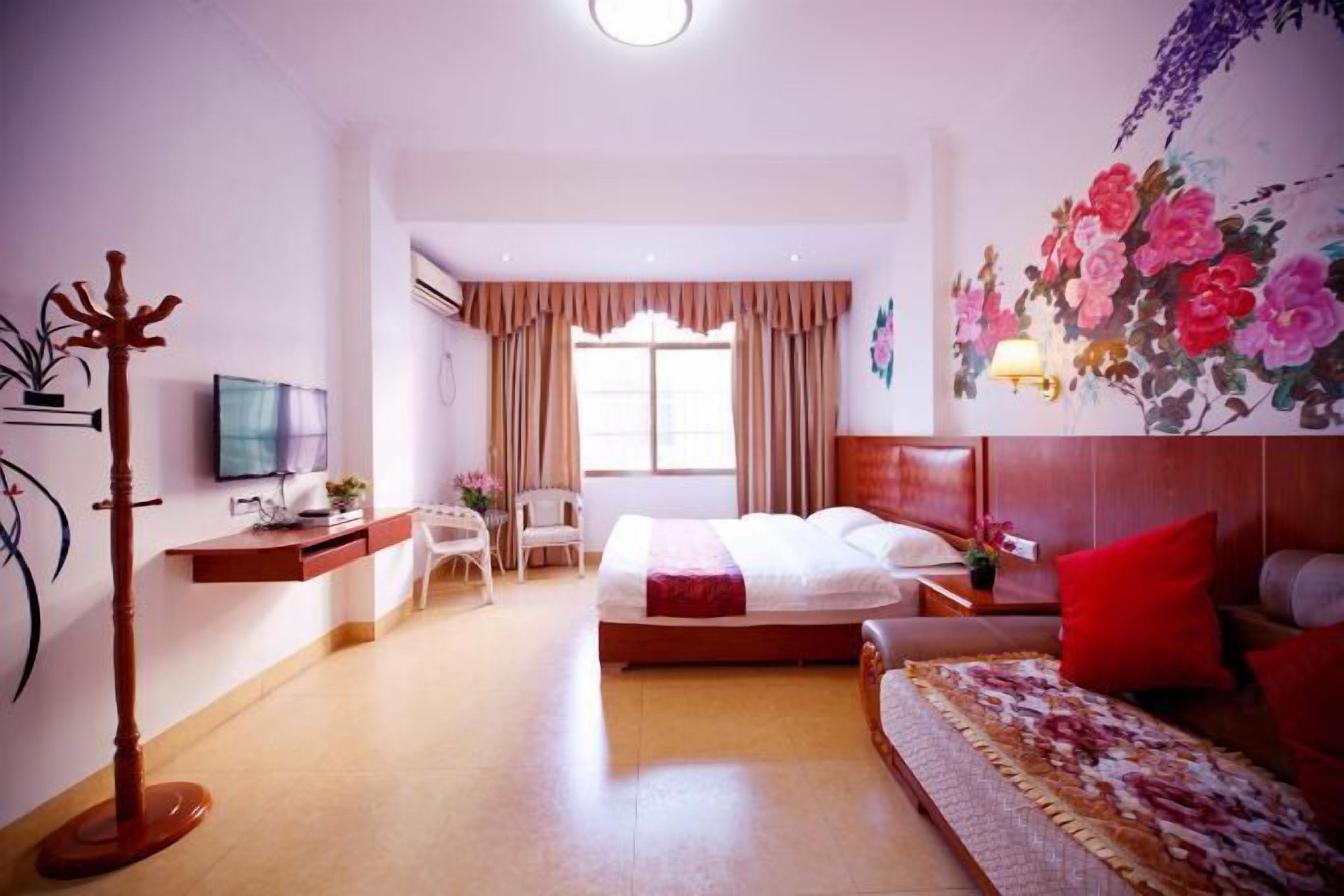 A hotel room with a bed, a desk with a TV, a chair, a coat rack, and a window with curtains.