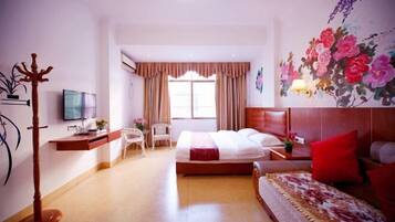 A hotel room with a bed, a desk with a TV, a chair, a coat rack, and a window with curtains.