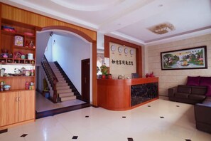 A hotel lobby with a reception desk, a staircase, a reception area, and a seating area. - Danxia Mountain Ruyi Inn (Renhua)