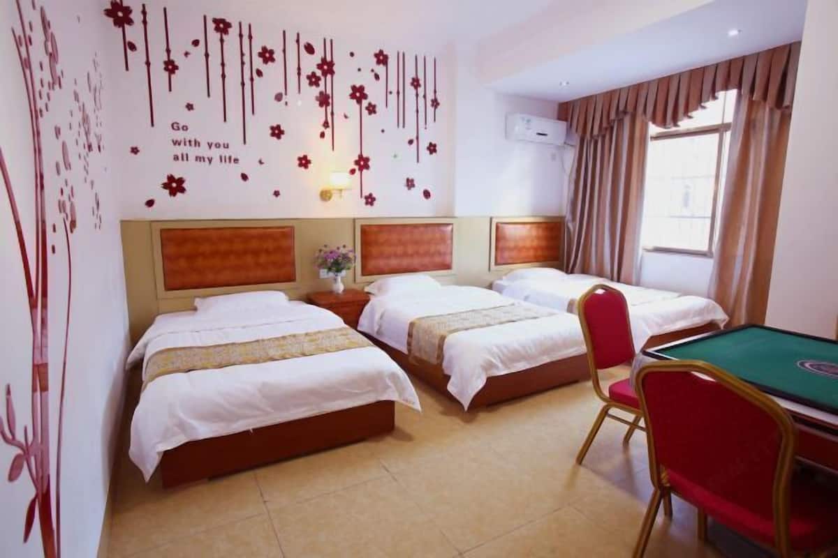 Habitación de hotel con tres camas, una mesa de billar y una pared decorada con motivos florales.