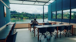 A conference room with a large window overlooking a scenic landscape. - Viajero Guatapé Hostel & Lake Club (El Peñol)