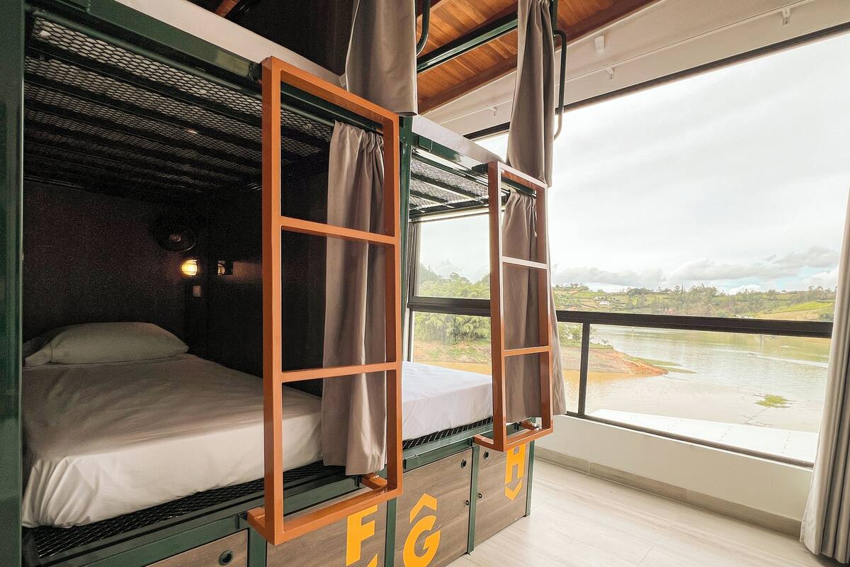 Une chambre avec des lits superposés offrant une vue sur une rivière et des collines.