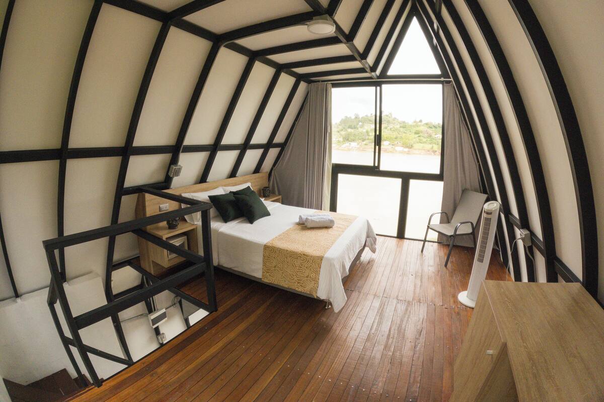 Une chambre à coucher avec un lit, une chaise, un bureau et une grande fenêtre.