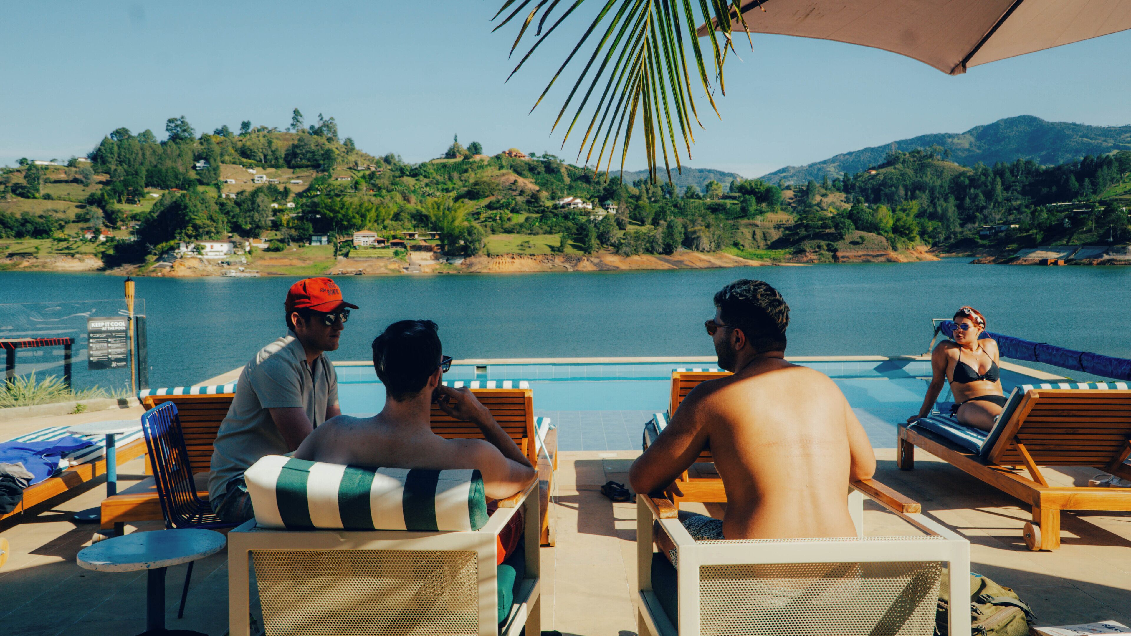Zona de piscina con sillones de descanso y vistas a un lago y colinas.