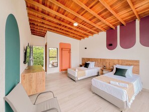 A hotel room with two beds, a wooden ceiling, a TV, and a view of greenery outside. - Viajero Guatapé Hostel & Lake Club (El Peñol)
