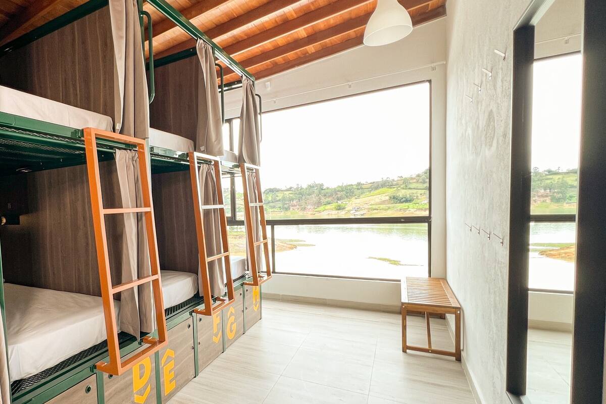 Une chambre avec des lits superposés donnant sur un lac, un plafond en bois et un luminaire suspendu.