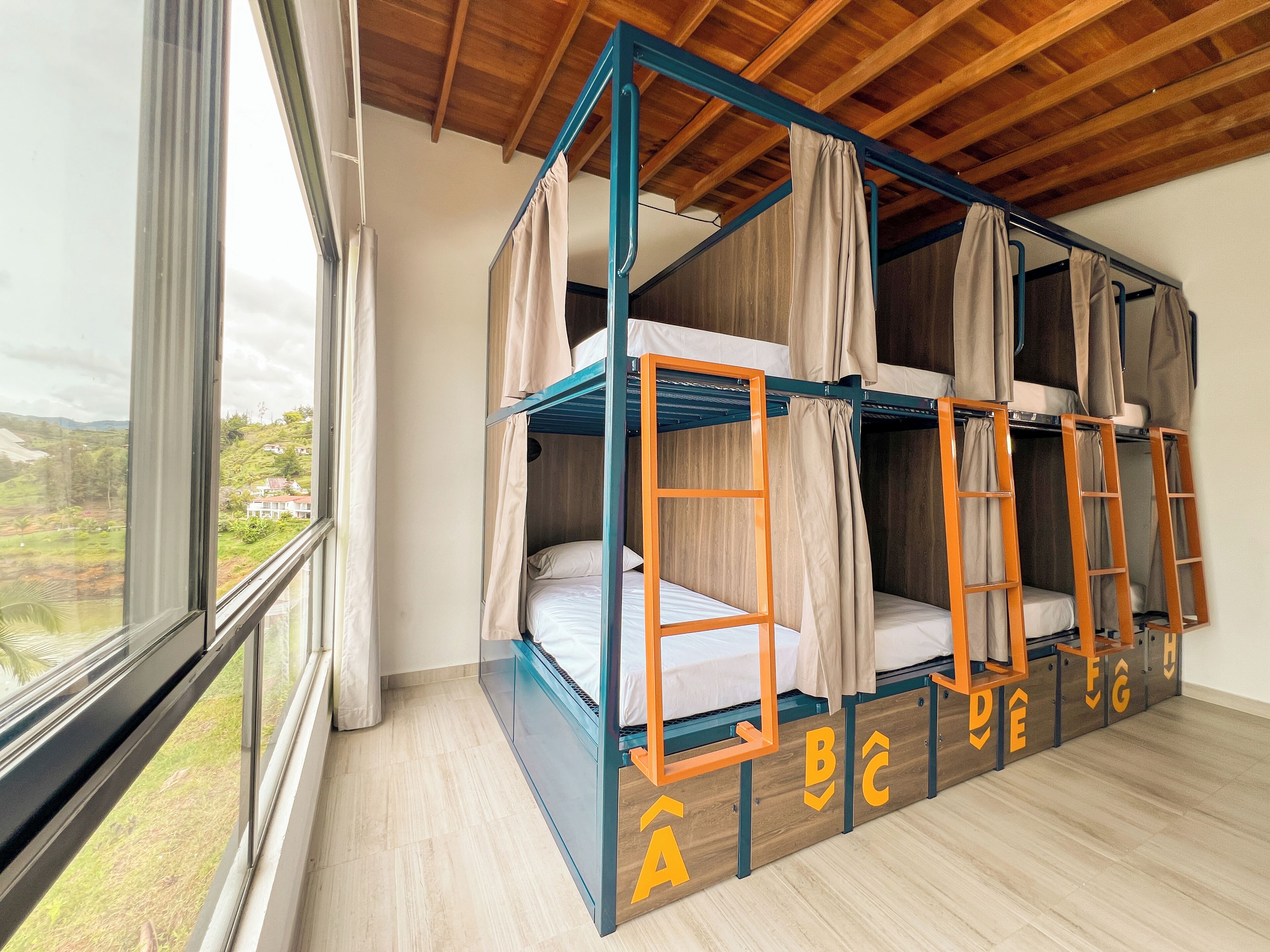 Habitación tipo dormitorio con literas, un ventanal grande y vistas a un paisaje montañoso.