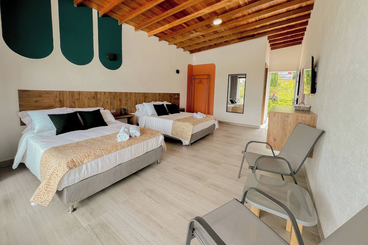 Une chambre d’hôtel avec deux lits, un plafond en bois, une petite table et une chaise.