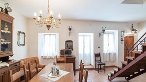 A dining area with a wooden table, chairs, a chandelier, and a staircase. - Belvilla by OYO Casa Angelica (Polino)