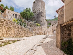 A cobblestone street leading to a historic stone tower.