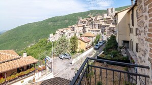 A hillside village with traditional stone buildings, a paved street, and a parked car. - Belvilla by OYO Casa Angelica (Polino)