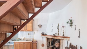 A rustic kitchen with wooden cabinets, a stove, and a fireplace. - Belvilla by OYO Casa Angelica (Polino)