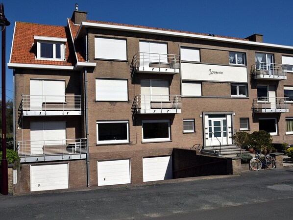 A multi-story residential building with a brick facade, white window shutters, and balconies. - Apartment in De Haan Near the Beach (De Haan)