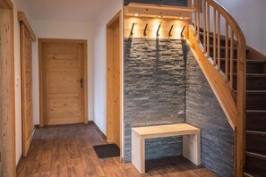 Eine Holztreppe mit einer Steinsäule, einer hölzernen Bank und einer Tür.