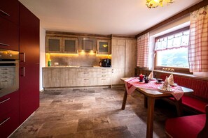 Eine kleine Küche mit Holzausstattung, einem Einbauofen und einem Essbereich mit Tisch für zwei Personen.