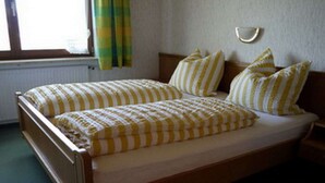 Ein Einzelbett mit Holzgestell und einer gelb-weißen Bettdecke.