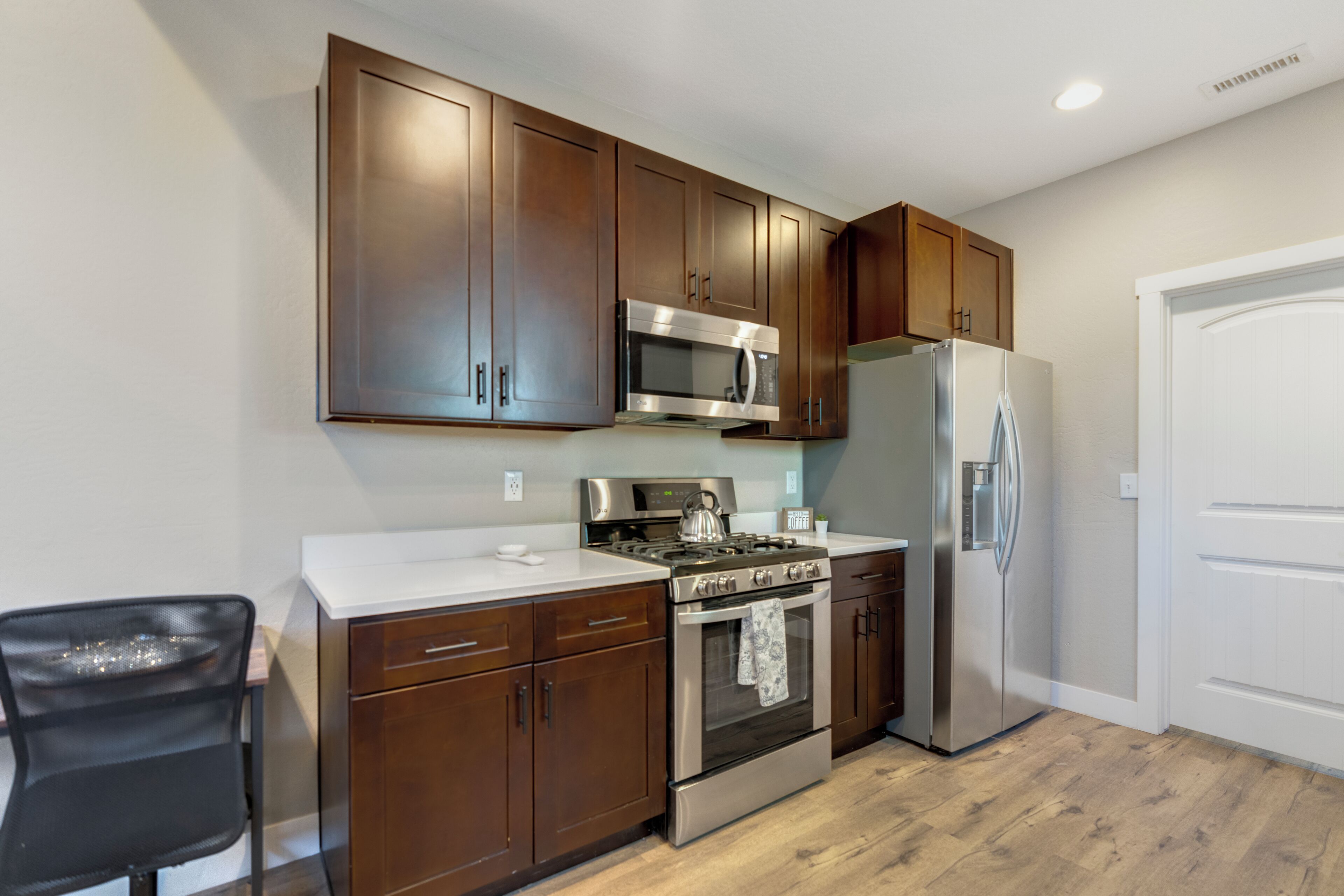 A kitchen with wooden cabinets, stainless steel appliances, and a white countertop.