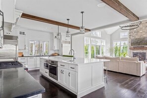 Une cuisine spacieuse avec des meubles blancs, un grand îlot central et une cheminée en pierre.