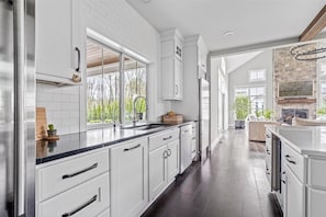 Une cuisine moderne avec des meubles blancs, un plan de travail noir et une vue sur l’extérieur.