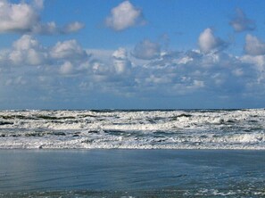 A beach with waves and a partly cloudy sky. - Old Printing House Holiday Apartment Bodoni (Norderney)