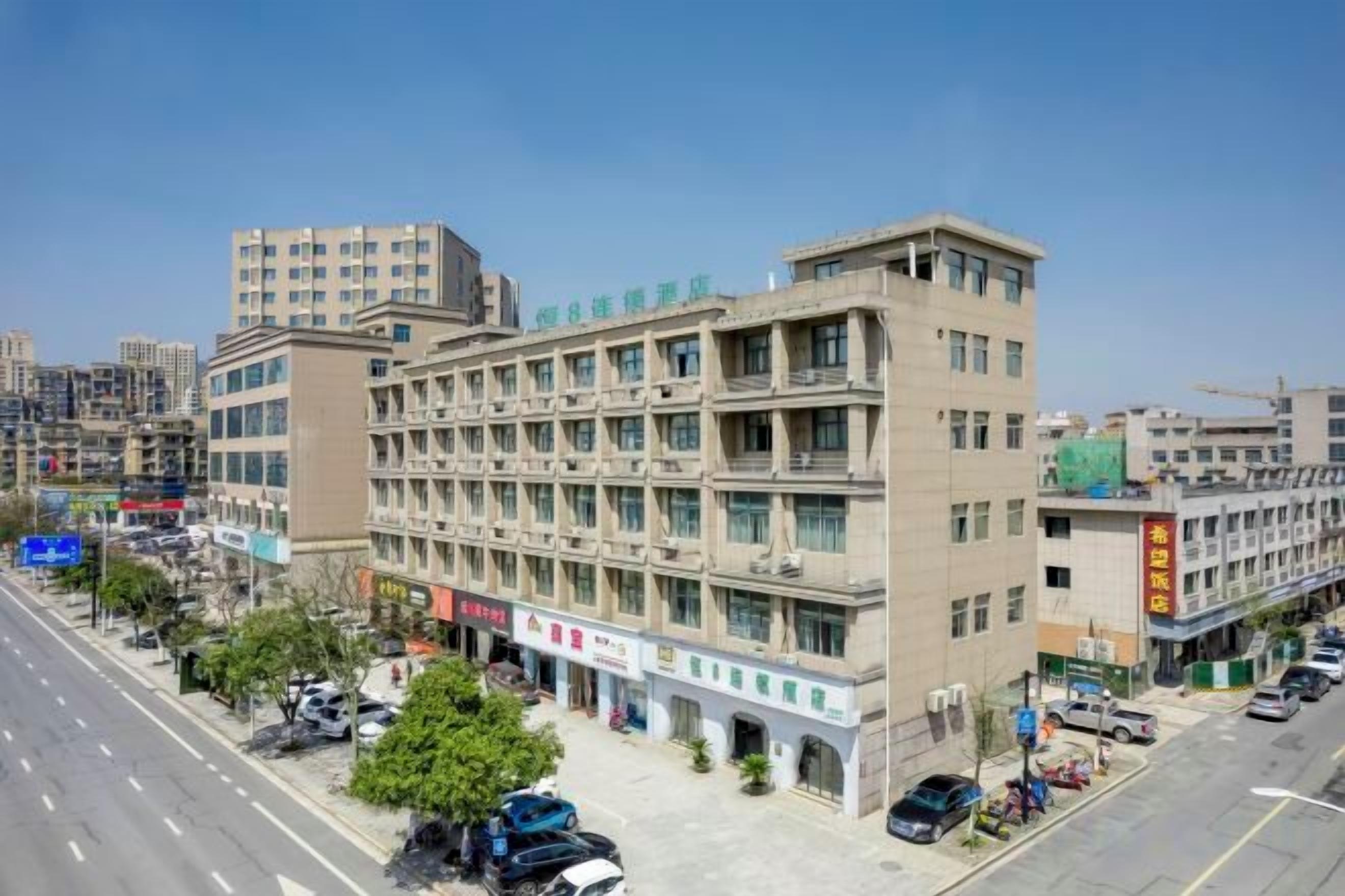 A multi-story building with a ground-level commercial area, multiple floors with windows, and a parking lot.