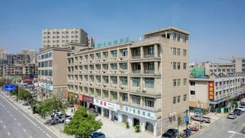 A multi-story building with a ground-level commercial area, multiple floors with windows, and a parking lot.