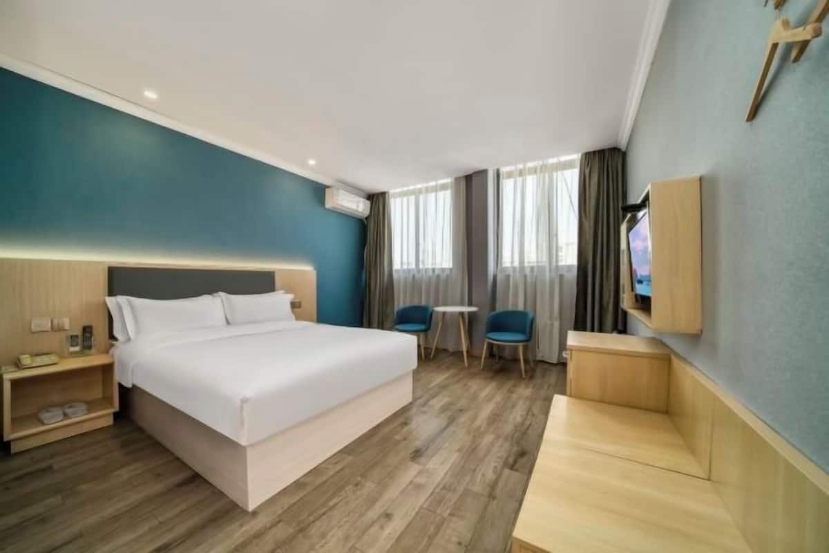 A hotel room with a large bed, bedside tables, a TV, and a seating area with chairs and a small table.