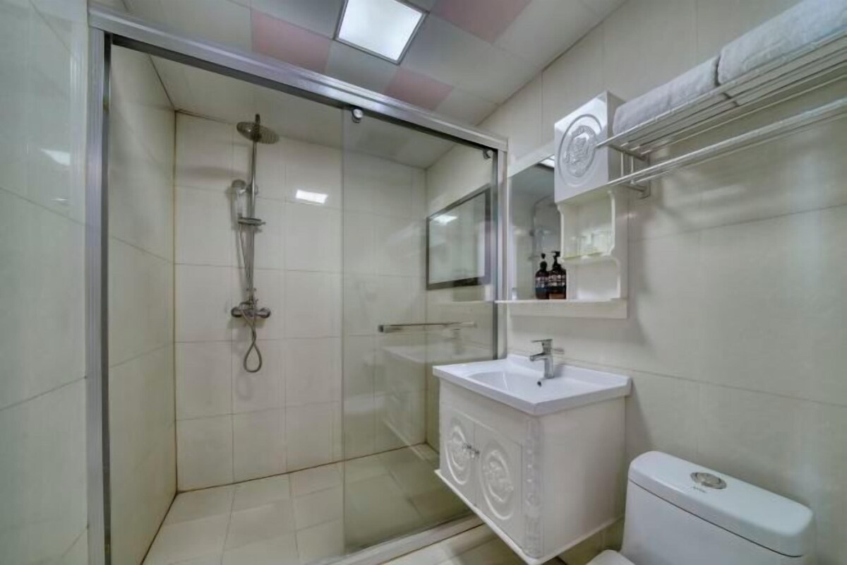 A modern bathroom with a glass-enclosed shower, a white sink, and a toilet.