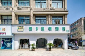 A hotel with a prominent sign, multiple floors, and a paved entrance area with potted plants. - Heng 8 Chain Hotel (Tonglu Xuesheng Road) (Tonglu)