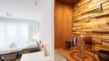 Een moderne slaapkamer met een houten wandpaneel, een nachtkastje met een glazen vaas en een bed met een wit hoofdeinde.