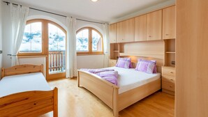 A bedroom with a wooden bed, a wooden nightstand, and a wardrobe. There are two windows with curtains. - Welcoming Apartment in Stummerberg With Terrace (Stummerberg)