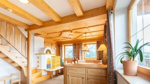 A wooden interior with a kitchen area, wooden staircase, and a window with curtains. - Welcoming Apartment in Stummerberg With Terrace (Stummerberg)