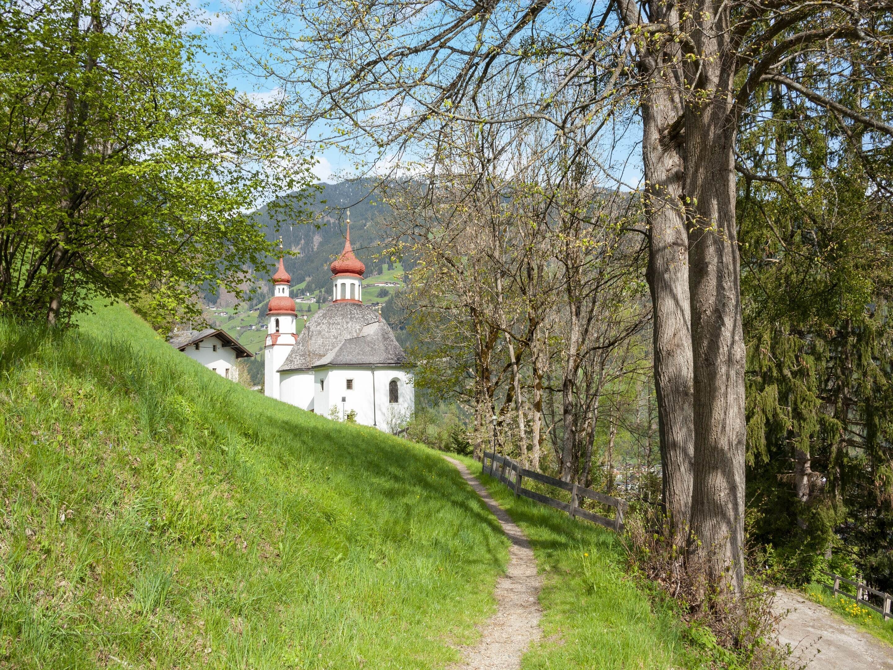 A white church with red domes on a hillside.