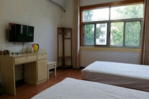 A room with a bed, a desk, a television, and a window with a view of trees. - Xiuning Yuanyuan Hotel (Xiuning)