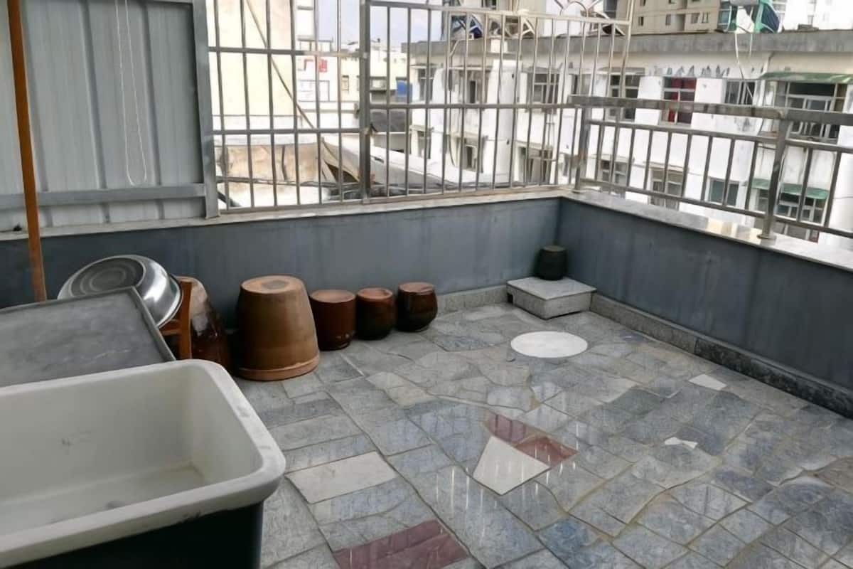 A rooftop terrace with a tiled floor, a metal container, and several wooden barrels.