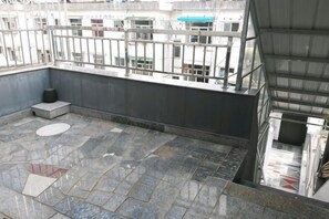 A rooftop terrace with stone flooring, a metal railing, and a view of buildings in the background. - Xiuning Yuanyuan Hotel (Xiuning)