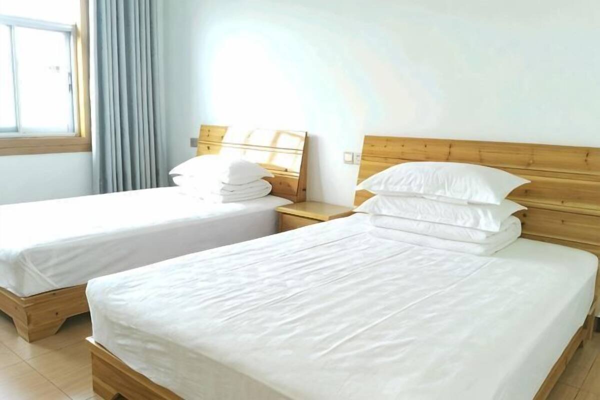 Two single beds with wooden headboards, white bedding, and a window with curtains.
