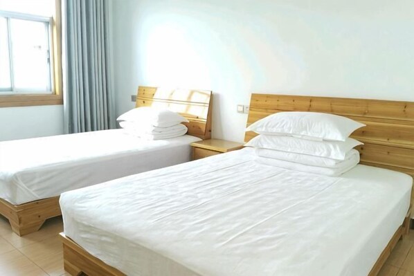 Two single beds with wooden headboards, white bedding, and a window with curtains.