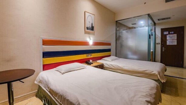 A hotel room with two beds, a small table, a mirror, and a door with a sign. - Airuisen Hotel (Zhoukou)